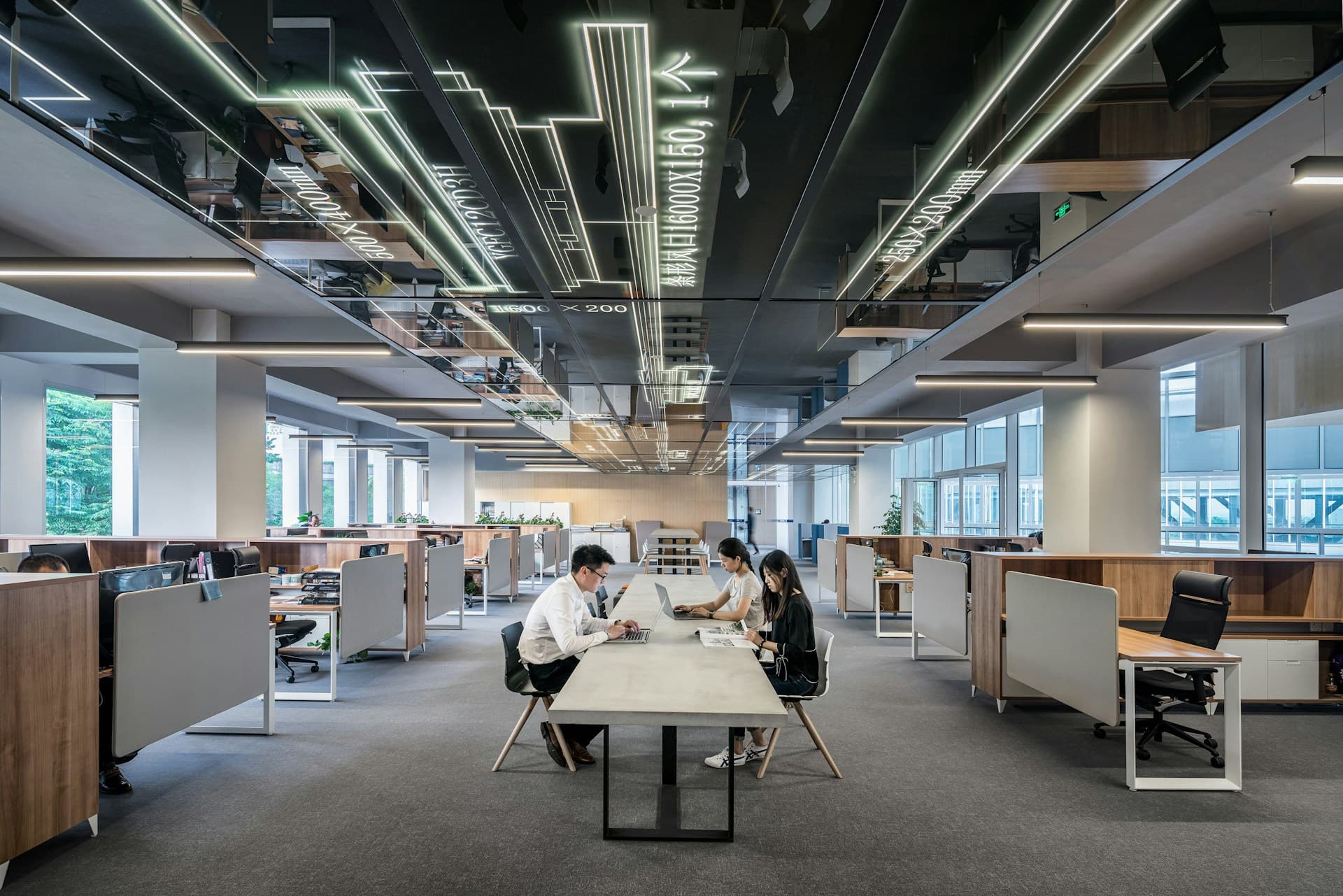 An open-plan office under long runs of ceiling light