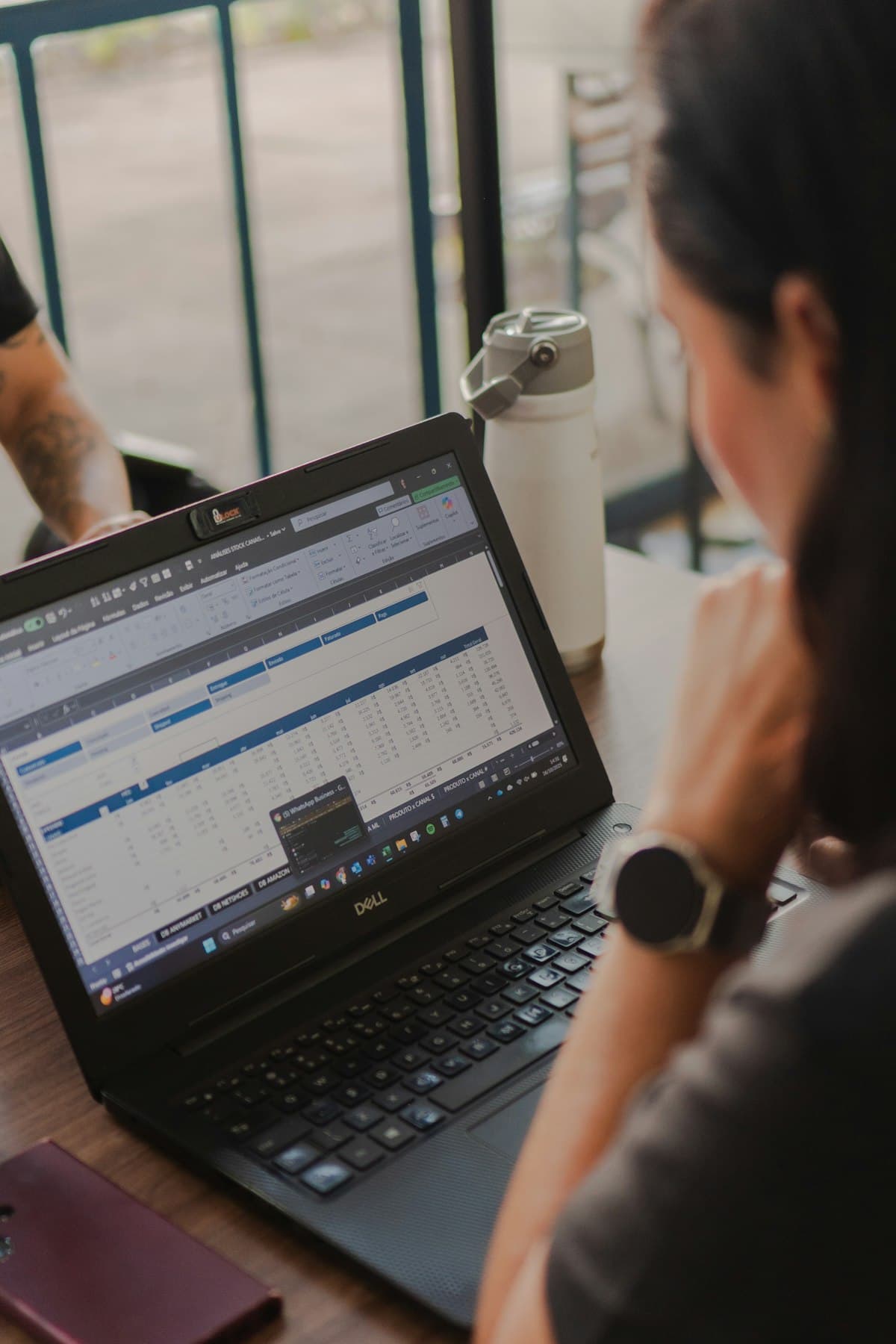 A laptop with a spreadsheet and a chat window open side by side